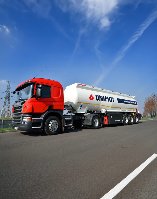 Ciężarówka handlowa z logo Kossbohrer zaparkowana na asfalcie. Środek transportu dostarczający ładunek z oznakowaniem UNIMOT.
