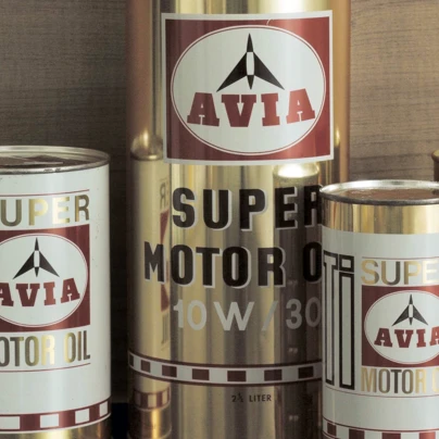 Różne rozmiary puszek aluminiowych z logo AVIA SUPER MOTOR OIL, w tym 1L, 2L i 0,5L. Klasyczny cylindryczny kształt z metalu.
